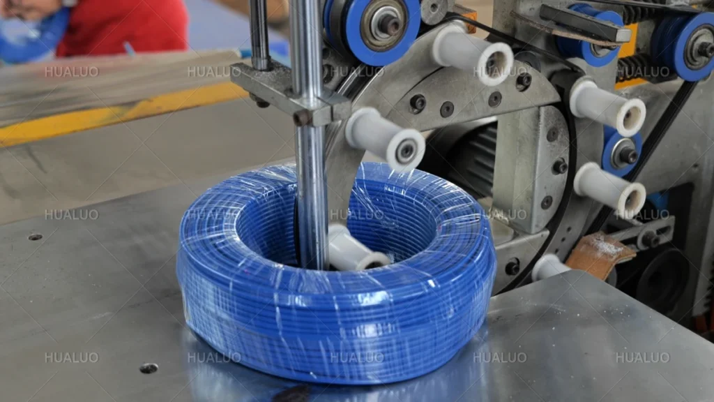 Packing and Dispatch Coiled blue cable wrapped in clear protective film on a Hualuo packaging machine.